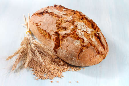 Fresh bread with wheat on the wooden background
