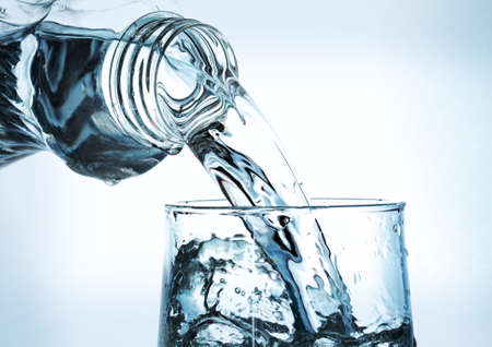 Pouring water from bottle into glassの写真素材