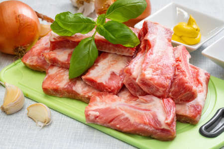 Raw pork ribs on a cutting board and  set of spices for cooking. Step on step recipe.の写真素材