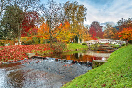Beautiful autumn landscape with bridge and reflection in riverの写真素材