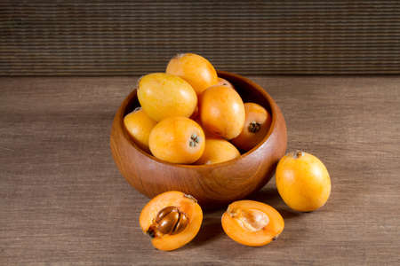 loquats in a wooden plate on a wooden backgroundの写真素材