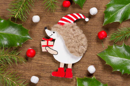 Christmas background with hedgehog and Holly leaves on a wooden backgroundの写真素材
