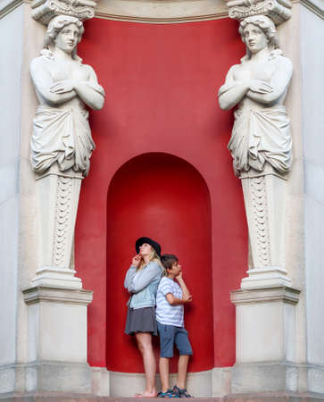 young woman and a boy stand in an arch with sculptures