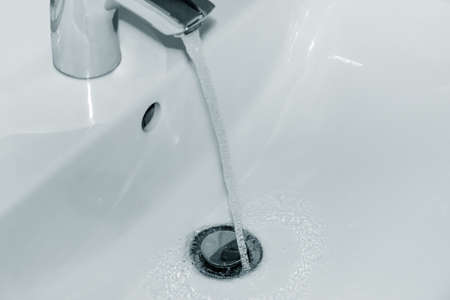 Flowing water from the tap into the washbasinの写真素材