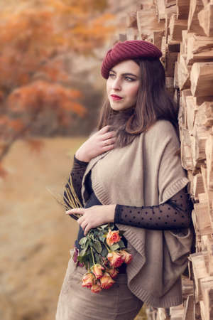 Portrait of a young woman with a bouquet of roses in the autumn season.の写真素材