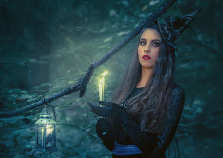 Young woman with a burning book in the forest. Halloween background.