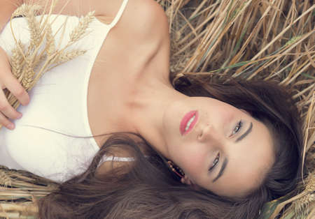Young woman resting in a wheat field on a sunny dayの写真素材