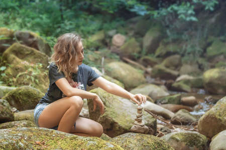 Young woman holds a pyramid of stones.の写真素材
