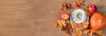 Autumn, fall leaves, a hot steaming cup of coffee, pumpkin and a warm sweater on a wooden table...