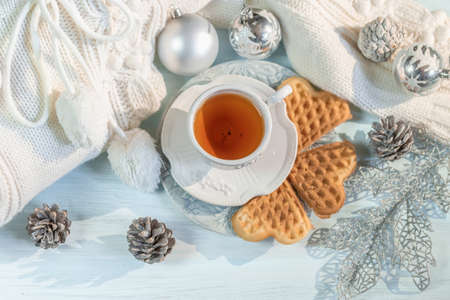 Winter, Christmas balls, a hot steaming cup of tea and a warm sweater on a wooden table background. の写真素材