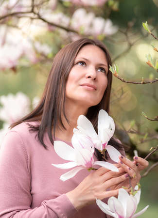Portrait of a middle-aged woman in blooming magnolias.の写真素材