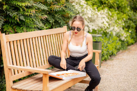 Young woman eating pizza in the parkの写真素材