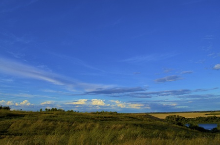 Big blue sky with various clouds in the background. taken on the South Saskatchewan River with various grass in the foreground and a Canola field in the backgroundの写真素材