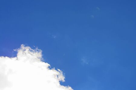 Bottom left shows a larger white cloud, the the rest is a sky blueの写真素材