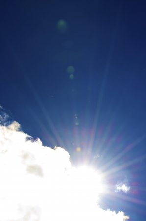 Sun shines on the top part of the Large cloud which covers the bottom part of  the picture while the rest is sky blueの写真素材