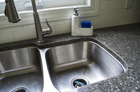 Angled picture of an under-mount sink with tap, and soap container.の写真素材