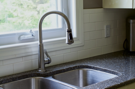 Stainless sink, tap with partial picture of window and white backsplash.の写真素材