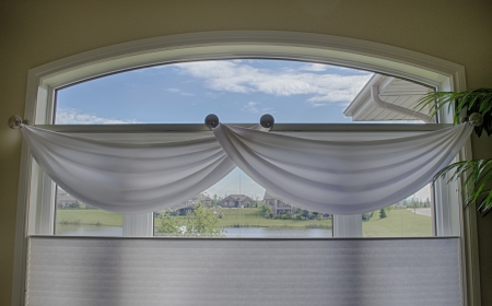 close view of a large window with white valances, and blinds. outside shows a blue sky with clouds.の写真素材