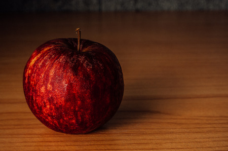 Red Apple on a wooden table with Dramatic lighting, Selective focus.の写真素材