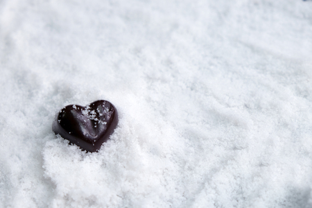 Assorted milk and dark chocolate heart on snow with copy space, Black Valentine's Day concept.の写真素材
