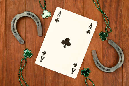 Concept of St. Patrick. green clover necklaces and lucky horseshoes with poker cards on wooden...