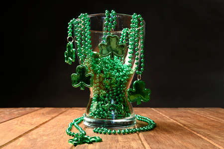 Concept of St. Patrick. Green  necklaces inside a jar on a black background.の写真素材