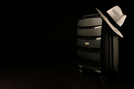 Holiday suitcase prepared with classic panama hat on black background, holiday concept, place for text.の写真素材