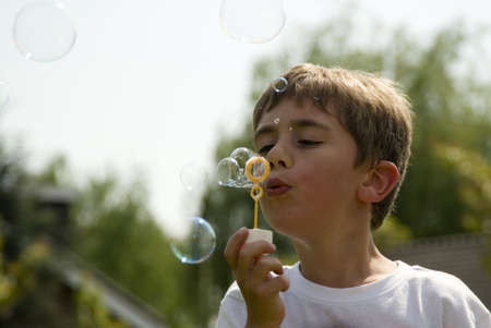 Boy blowing soap bubblesの写真素材