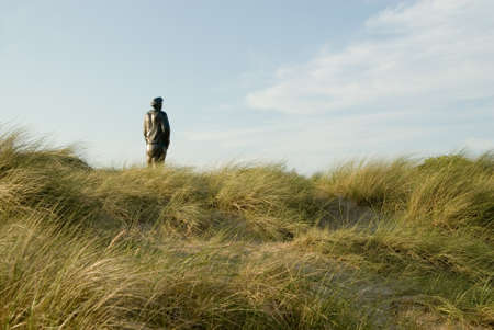 a statue standing in the dune and looking at the seaの写真素材