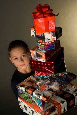 a boy holding a pile with christmaspresentsの写真素材