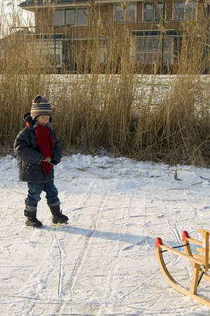a young boy with his sled on iceの写真素材