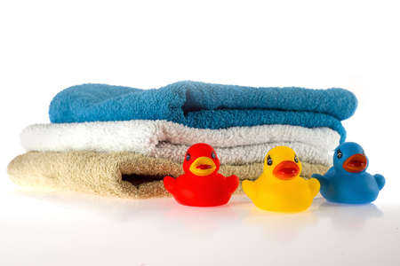 three towels and three rubber ducks on white