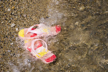 colorful slippers wash away in the seaの写真素材