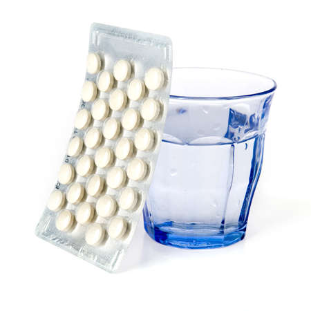 a blue glass and a blister with pills on a white backgroundの写真素材