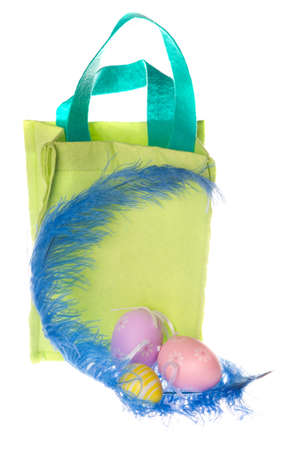 three colorful easter eggs  with a blue feather and a bagの写真素材