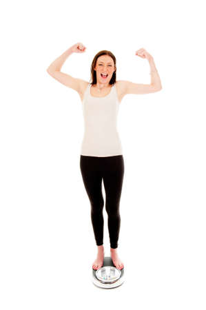 a girl on a weighing scale, celebrating her success of loosing weightの写真素材