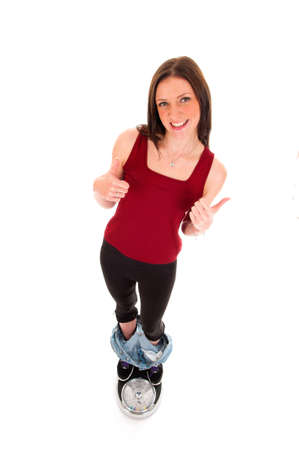 a girl on a weighing scale, celebrating her success of loosing weightの写真素材