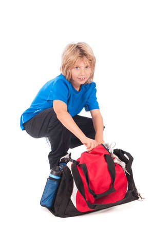 a young boy, ready for going to play football, with his sportbag and footballの写真素材