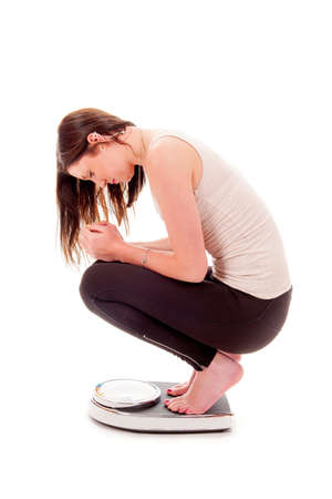 a girl on a weighing scale, disappointed of loosing to too little weightの写真素材