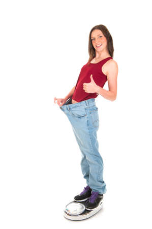 a girl on a weighing scale, celebrating her success of loosing weightの写真素材
