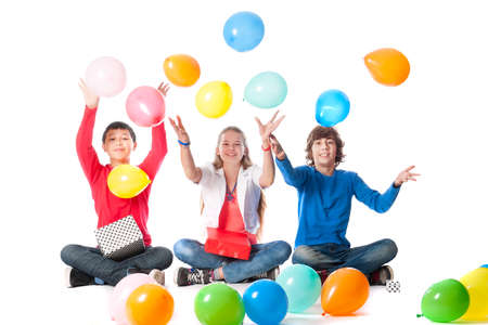 a birthday girl with her two friends with presents and balloons on a white backgroundの写真素材