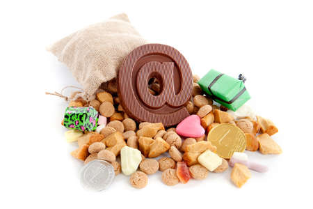 a jute bag full of pepernoten, a atpersand made of chocolate and a lot of candies on a white backgroundの写真素材