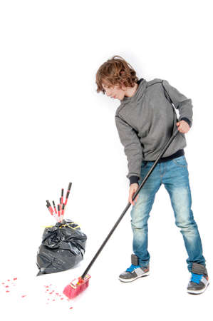 a teenage boy with a broom, cleaning the mess on new years dayの写真素材