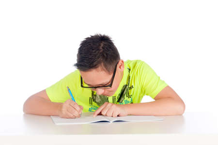 a teenage boy is writing in a exercise book on a white backgroundの写真素材