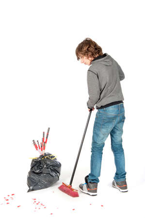 a teenage boy with a broom, cleaning the mess on new years dayの写真素材
