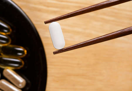 Someone using chopsticks to take supplements.