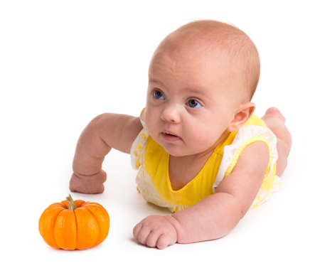 Baby girl with a small pumpkin isolated on a white backgroundの写真素材