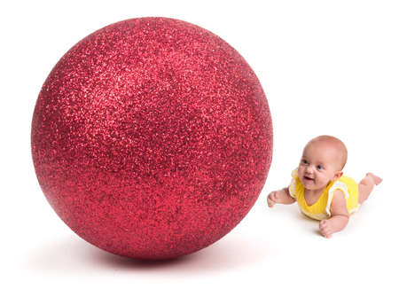 Cute Baby smiling at a Huge Christmas Ornament on whiteの写真素材