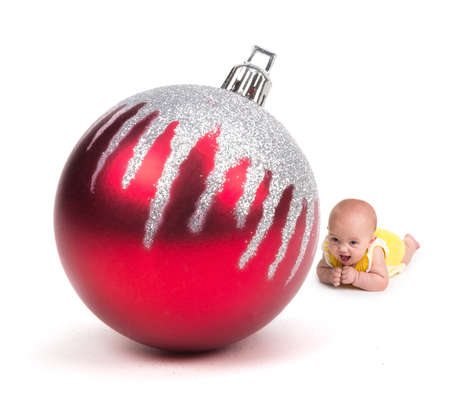 Cute Baby smiling at a Huge Christmas Ornament on whiteの写真素材