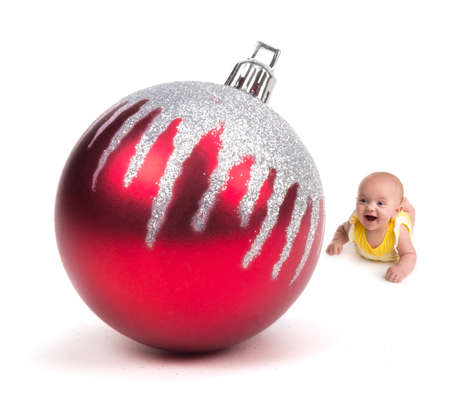 Cute Baby smiling at a Huge Christmas Ornament on whiteの写真素材